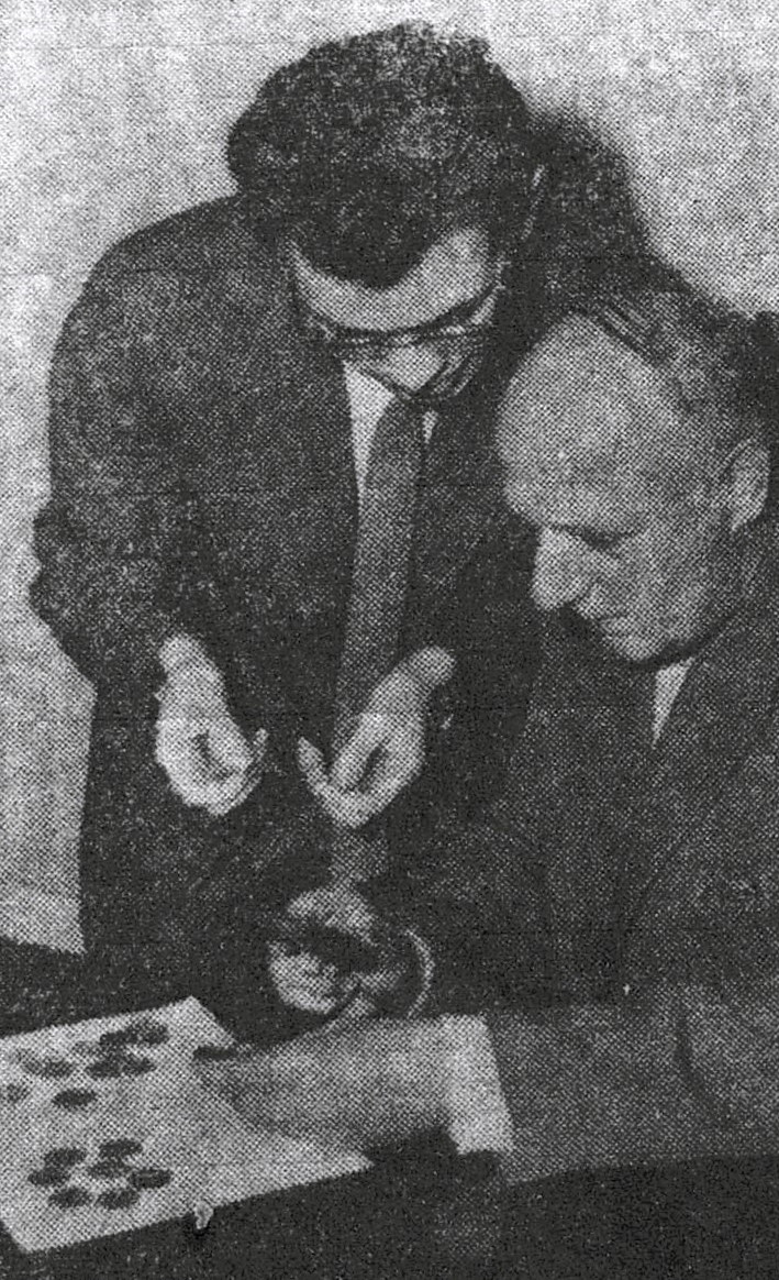 Gemeindeinspektor Hans Meyer (stehend) und Gemeindeangestellter Josef Wartenberg betrachten mit einer Lupe die auf einem Baugrundstück in Wickrath gefundenen Münzen. WZ Rheydt 11.10.1958